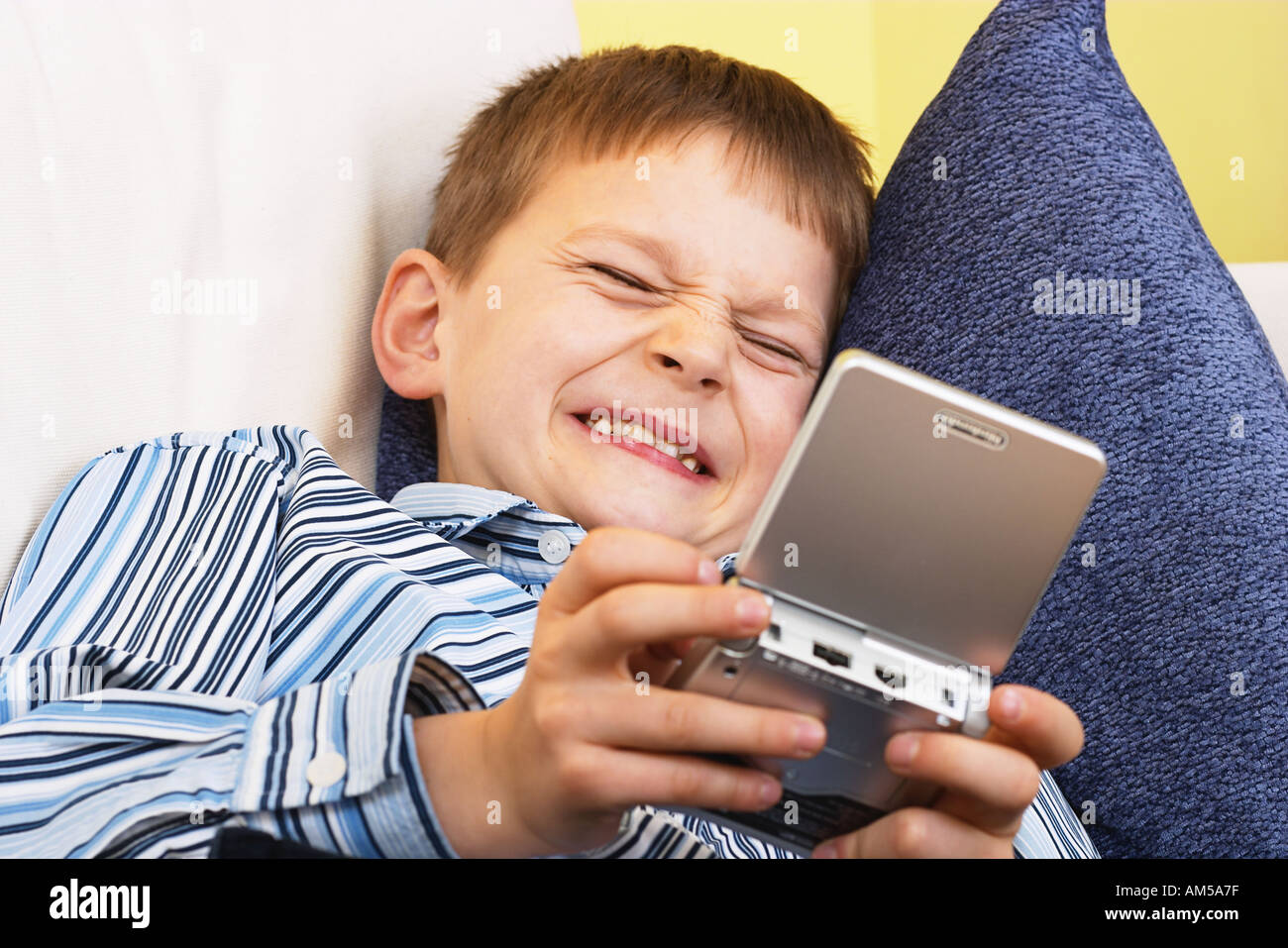 Junge auf Sofa mit Gameboy Spielen Stockfoto
