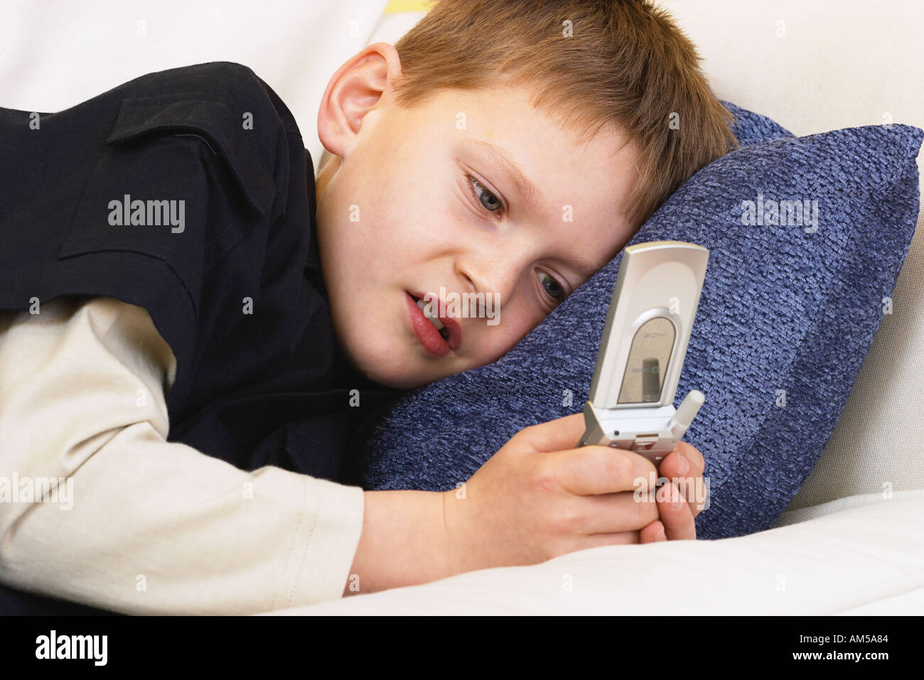 Junge liegend auf einem Sofa SMS auf dem Handy Stockfoto