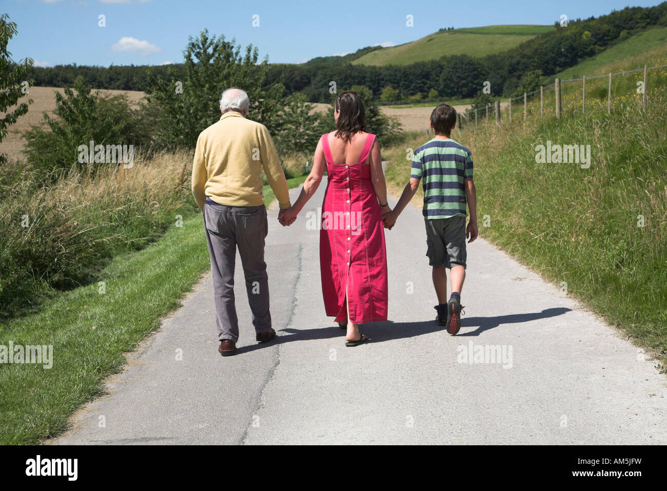 Drei Generationen der Familie gehen in die Ferne entlang Landstraße Rockley, Wiltshire, England Stockfoto