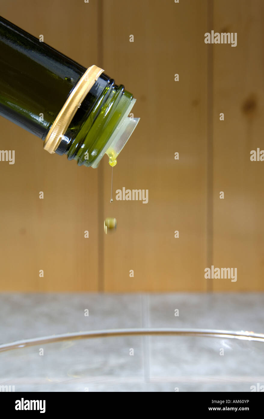 Die letzten Tropfen fallen aus dem Flaschenhals eine grüne Flasche Olivenöl Stockfoto