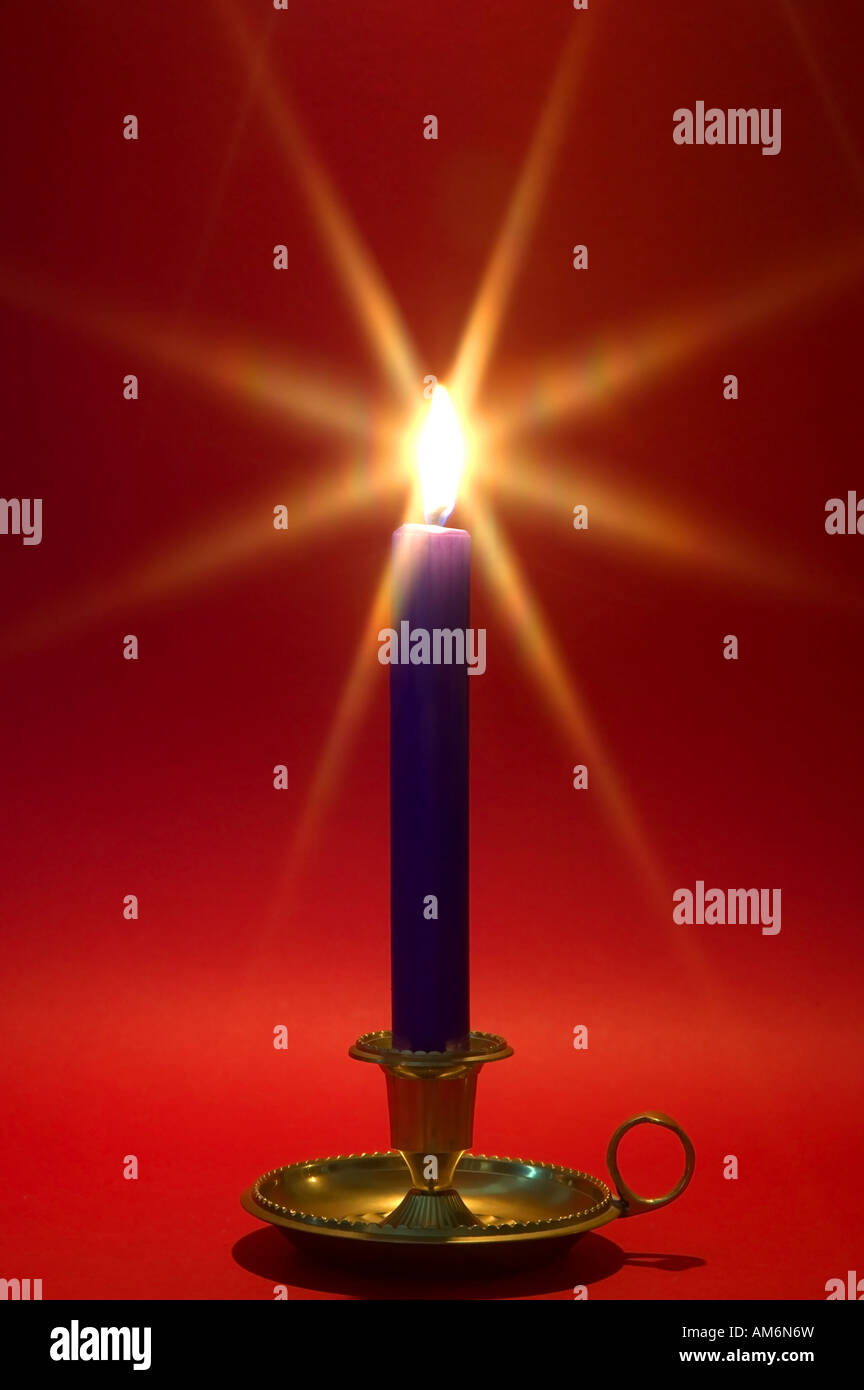 Blaue Kerze in einem Messing-Halter steigen gegen einen roten Hintergrund Weihnachtsthema Stockfoto