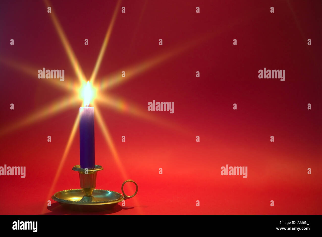 Eine blaue Kerze in einer Messing-Halterung gegen einen roten Hintergrund Weihnachtsthema Stockfoto