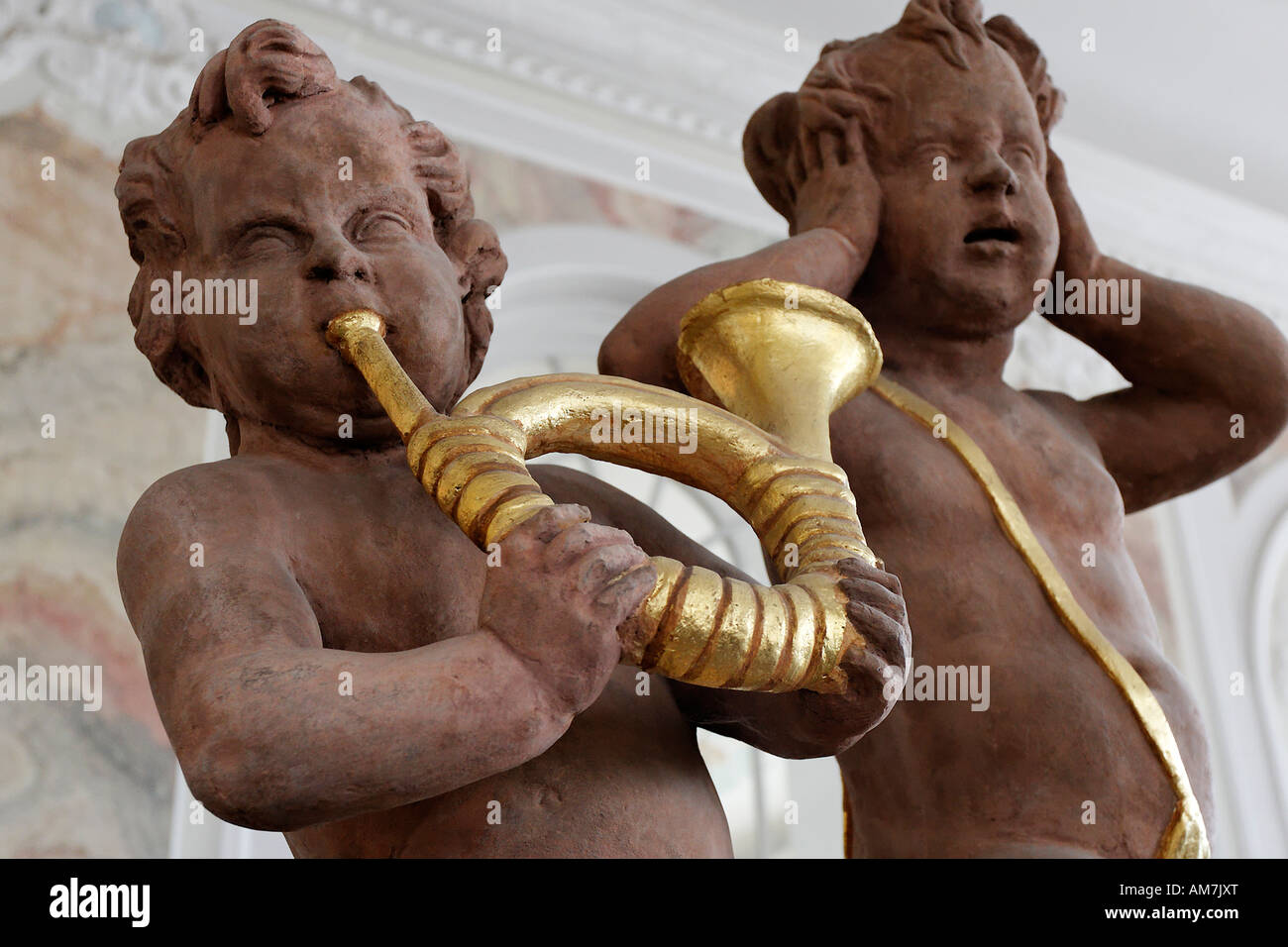 Ein Putto weht ein goldenes Horn, andere setzen die Hände über die Ohren, Palast des Kurfürsten, Trier, Rheinland-Pfalz, Keim Stockfoto