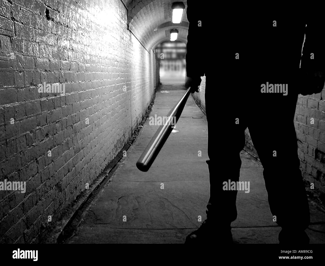 Unbekannte Schläger mit einem Baseballschläger in einem Tunnel, schwarz / weiß Stockfoto