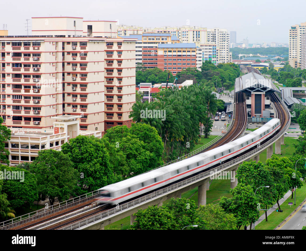 Ein Zug bewegt sich weg von einer Station unter öffentlichen Wohnsiedlungen in Singapur The Mass Rapid Transit Stockfoto