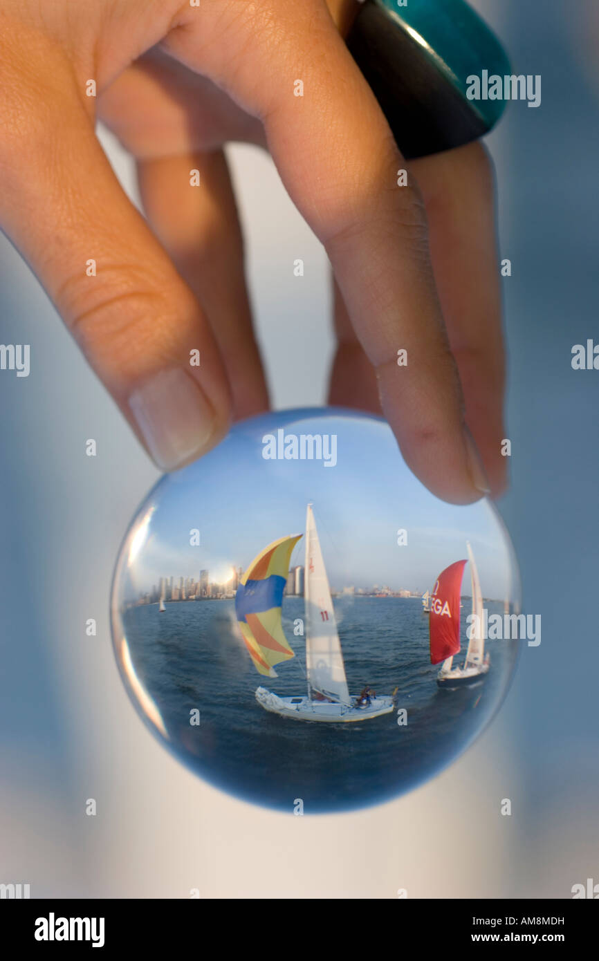Segelboot in einem Glas, einer Frau mit einer Kugel mit einem Segelboot hinter einander im Glas Stockfoto