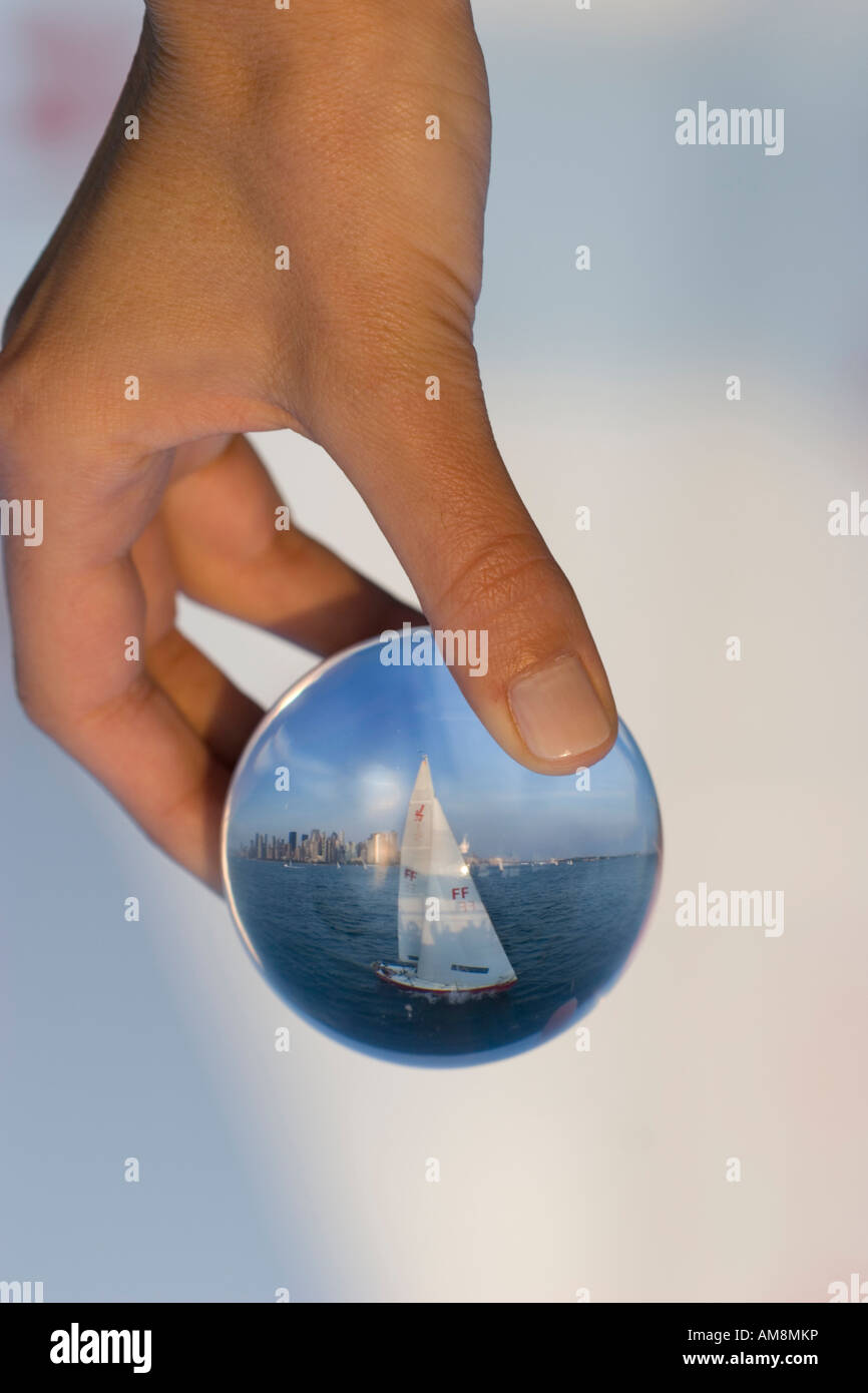 Segelboot in einem Glas, einer Frau mit einer Kugel mit einem Segelboot hinter einander im Glas Stockfoto