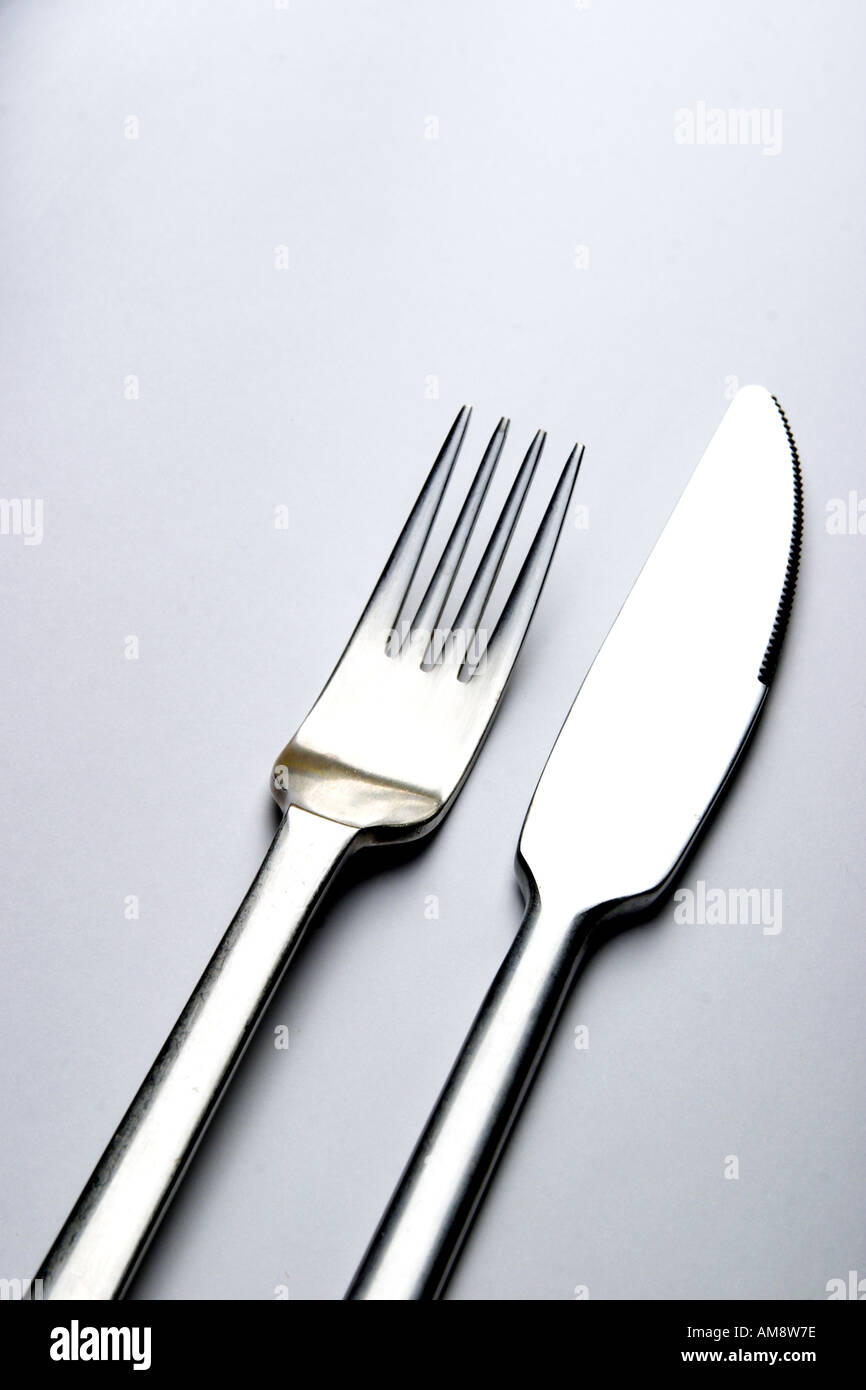 Abstraktes Bild von Messer und Gabel liegen nebeneinander auf einer weißen Fläche Stockfotografie