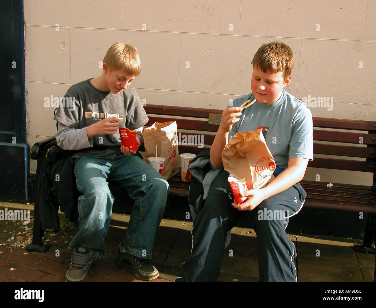 Zwei Jungs sitzen auf Bank Essen Fast food Stockfoto