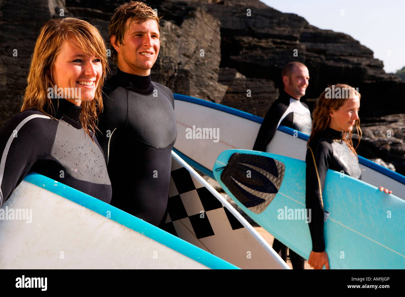 Vier Personen stehen mit Surfbrettern Lächeln auf den Lippen. Stockfoto