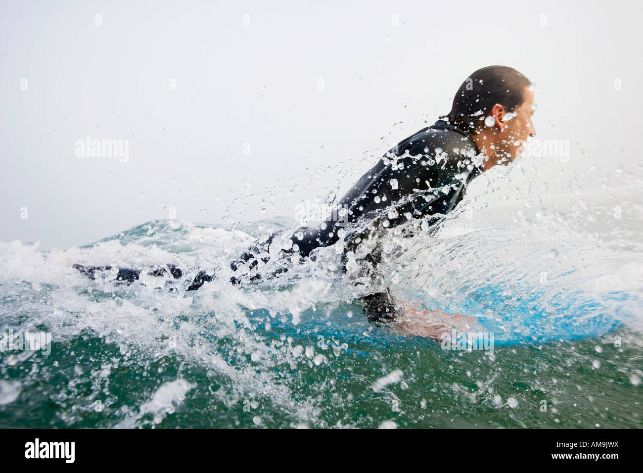 Mann auf Surfbrett im Wasser plantschen. Stockfoto