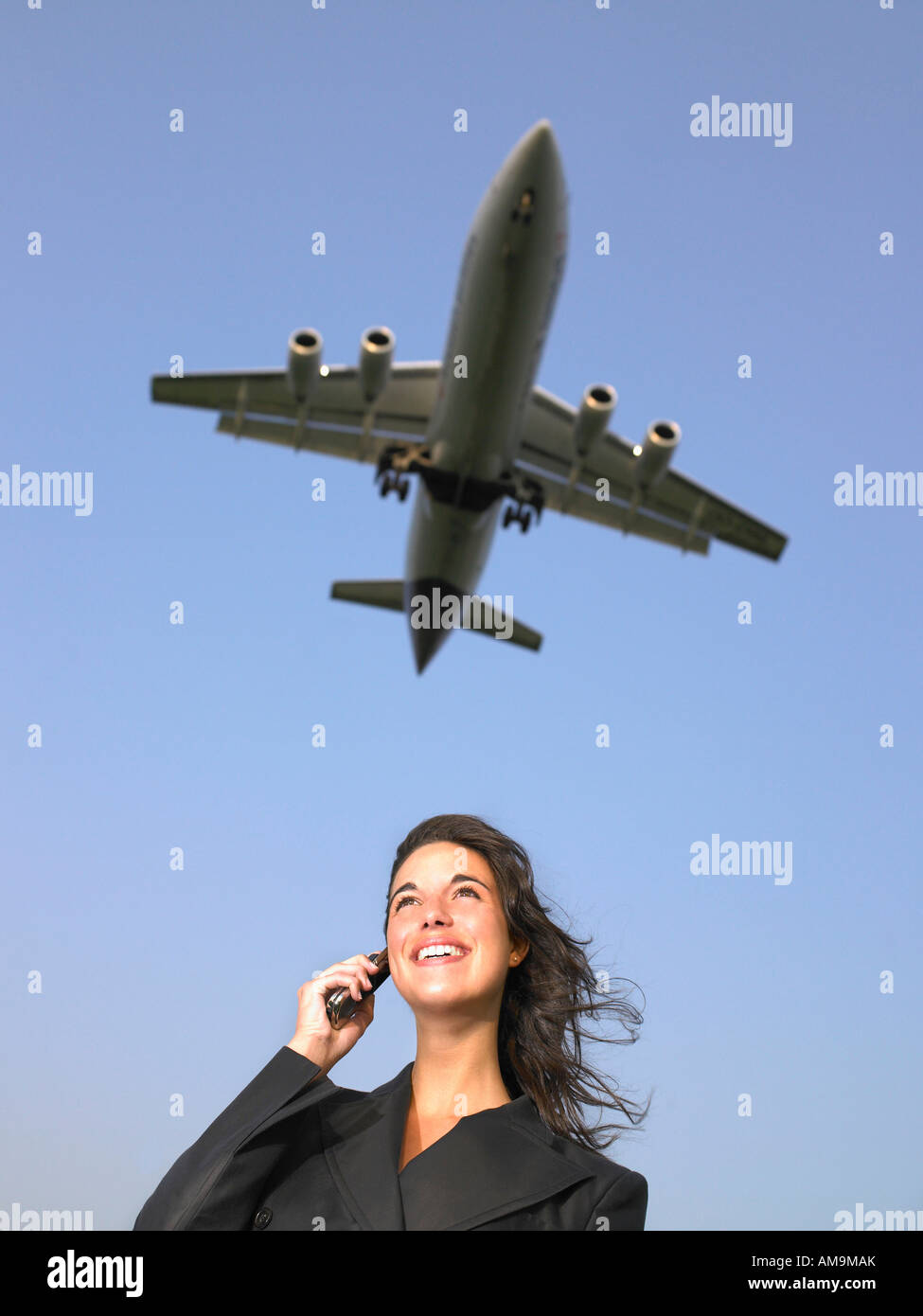 Frau auf Handy lächelnd mit dem Flugzeug fliegen overhead. Stockfoto