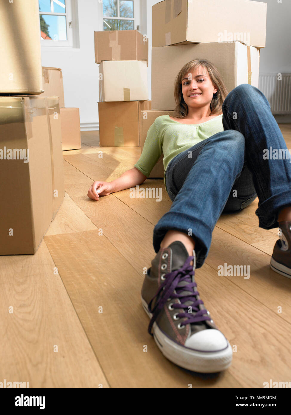 Frau mit beweglichen Kästen um sie lächelnd am Boden liegend. Stockfoto