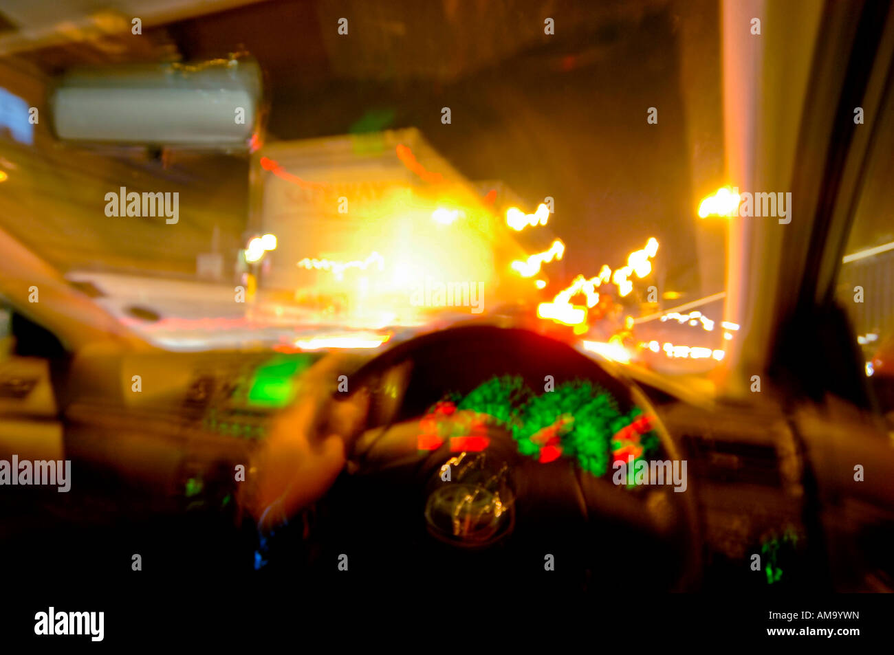 Mann mit Lenkrad mit Hand Auto im Feierabendverkehr mit LKW in Windschutzscheibe sichtbar in der Nacht Stockfoto