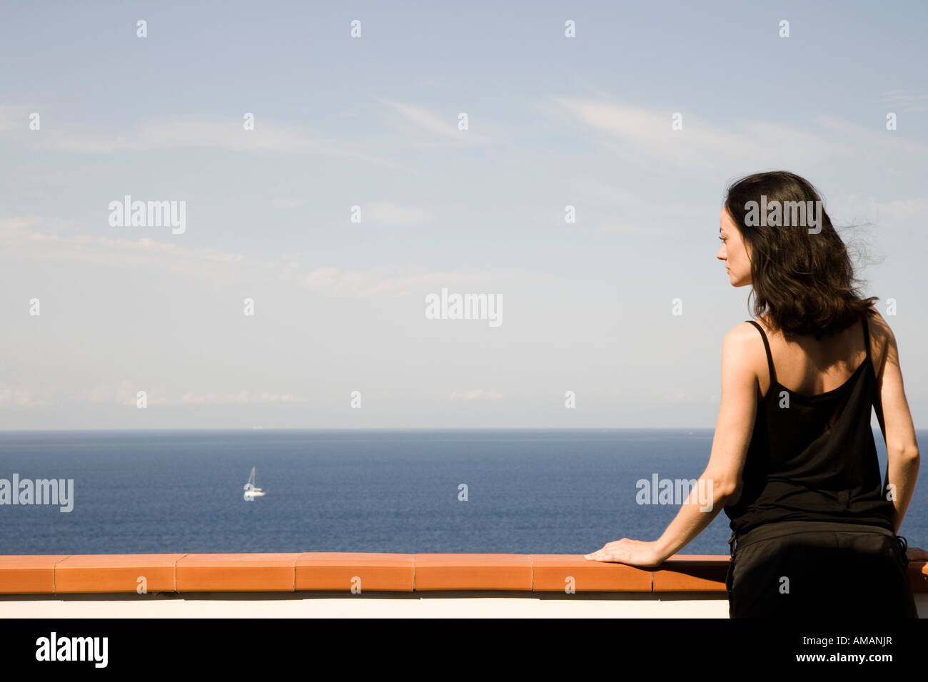 Eine Frau steht auf einem Balkon mit Blick auf das Meer Stockfoto