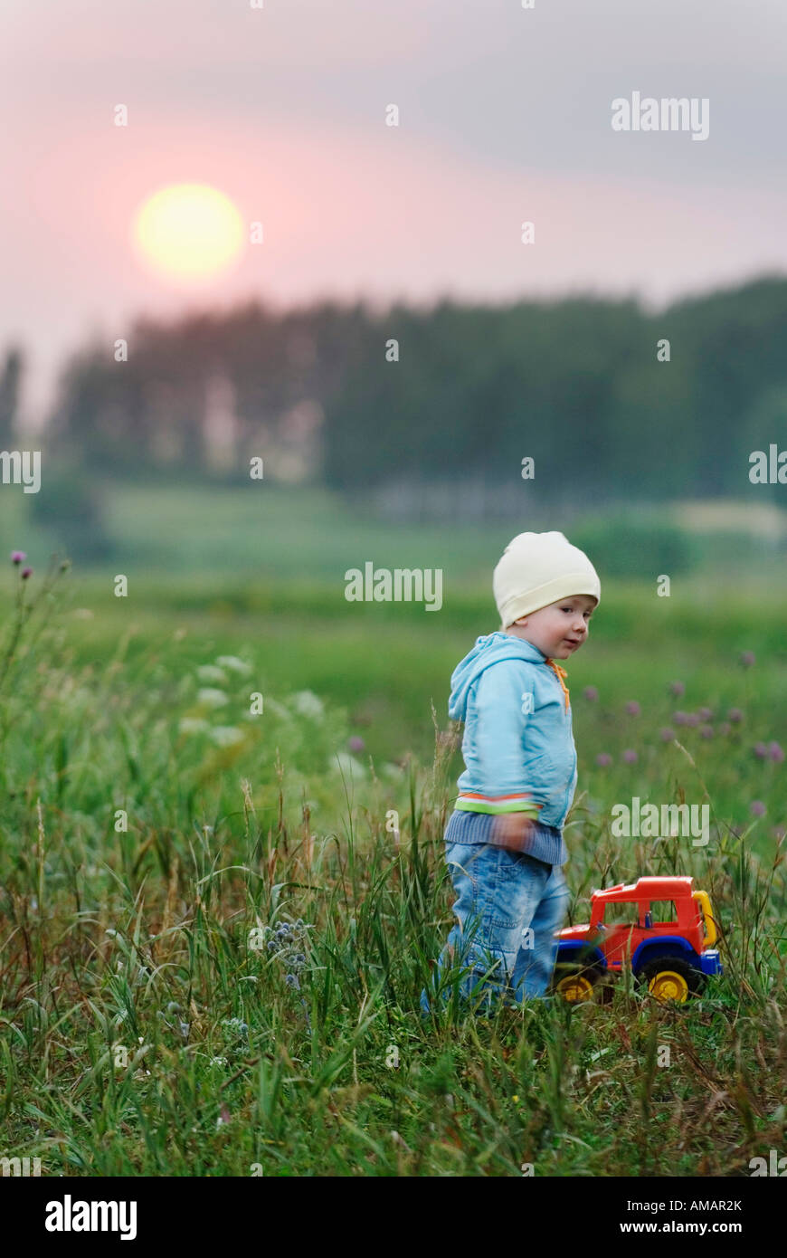 Ein kleiner Junge mit einem Spielzeug-LKW in einem Feld stehen Stockfoto