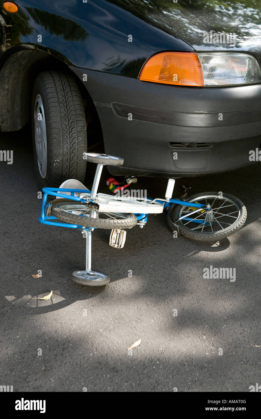 Ein Kind Fahrrad auf der Straße unter einem Auto liegen Stockfoto
