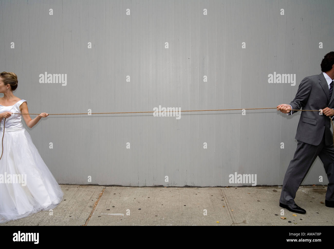 Eine Braut und Bräutigam ziehen ein Seil in verschiedene Richtungen Stockfoto