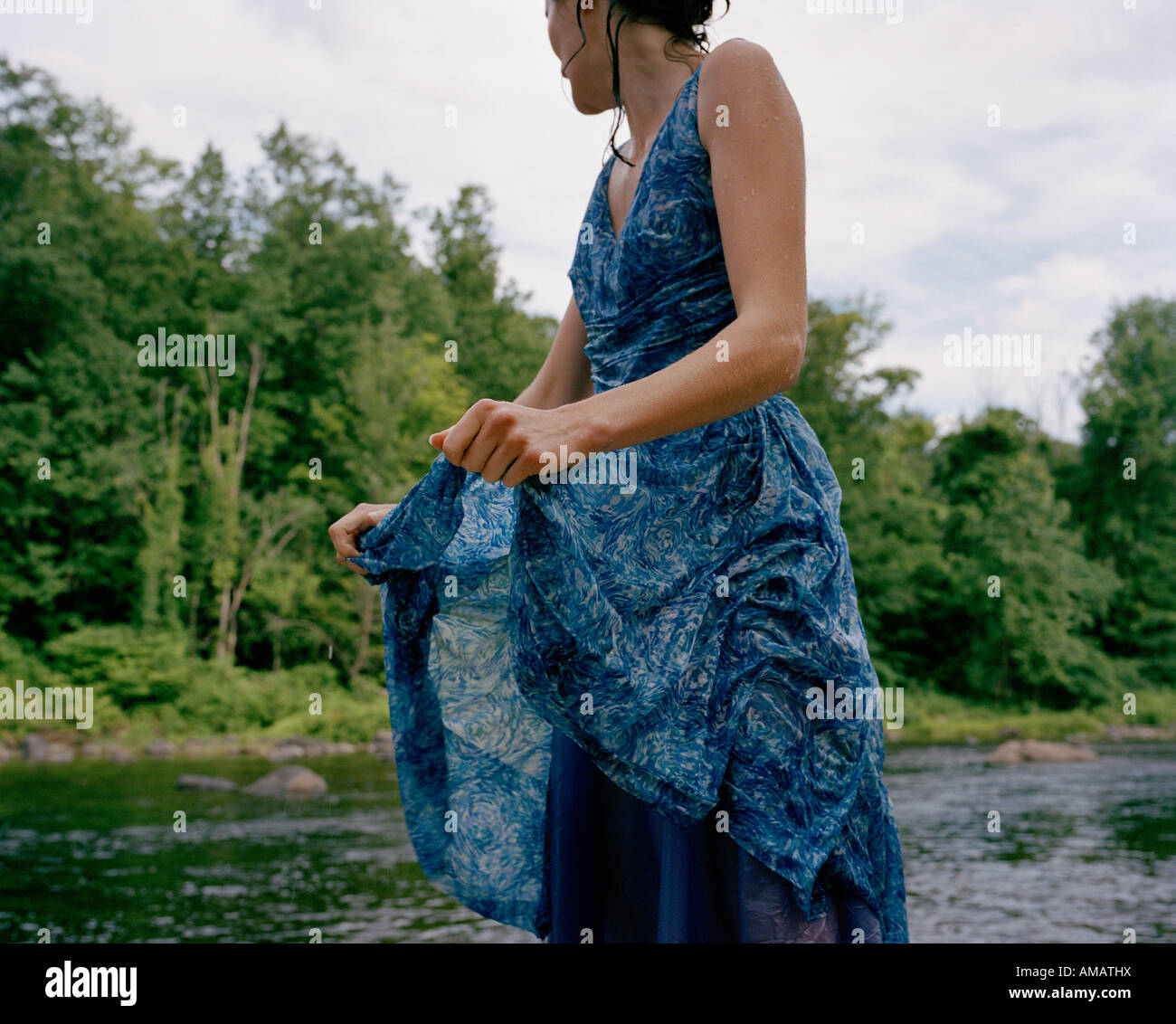 Eine Frau stand neben einem Fluss in einem nassen Kleid Stockfoto