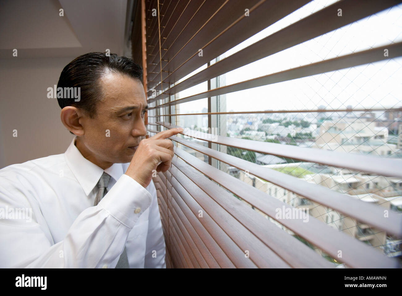 Ein Geschäftsmann Blick durch Fenster-Vorhänge Stockfoto
