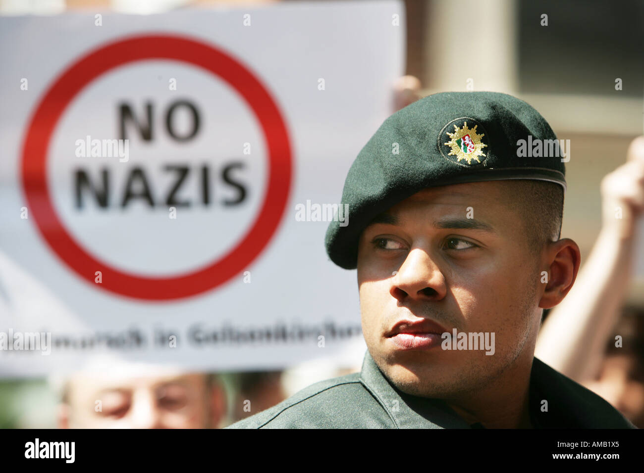 Polizist bei einer Demonstration der ultra rechtsextremen NPD Partei. Poster der eine Gegendemonstration. Stockfoto