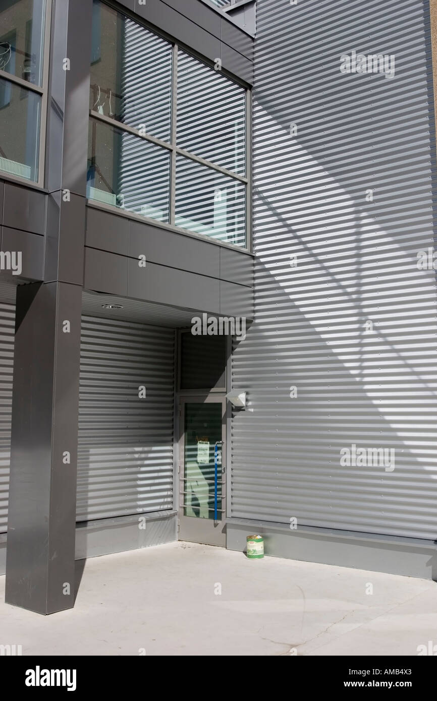 graue Wand mit horizontalen Linien und Licht reflektierende Fenster Stockfoto