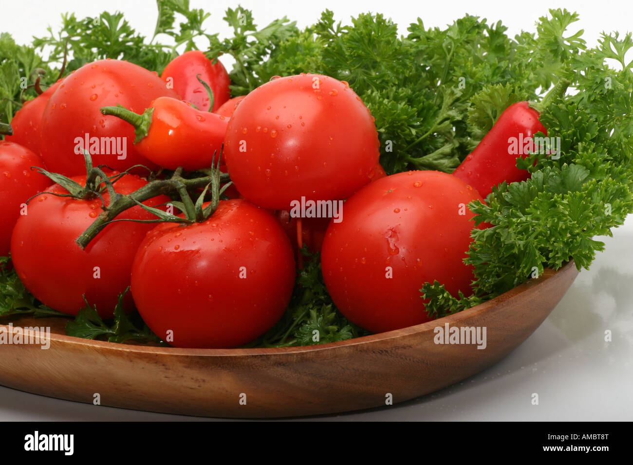 Bio rote Tomaten Korb Rebe mit Petersilie auf Platte Schale Studio Bild auf weißem Hintergrund auf Tisch Stockfoto