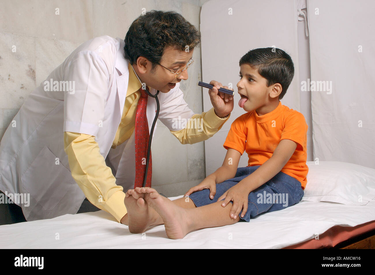 Indischer Doktor, der Kehle des kleinen Jungen mit Fackel überprüft, MR#560&637 Stockfoto