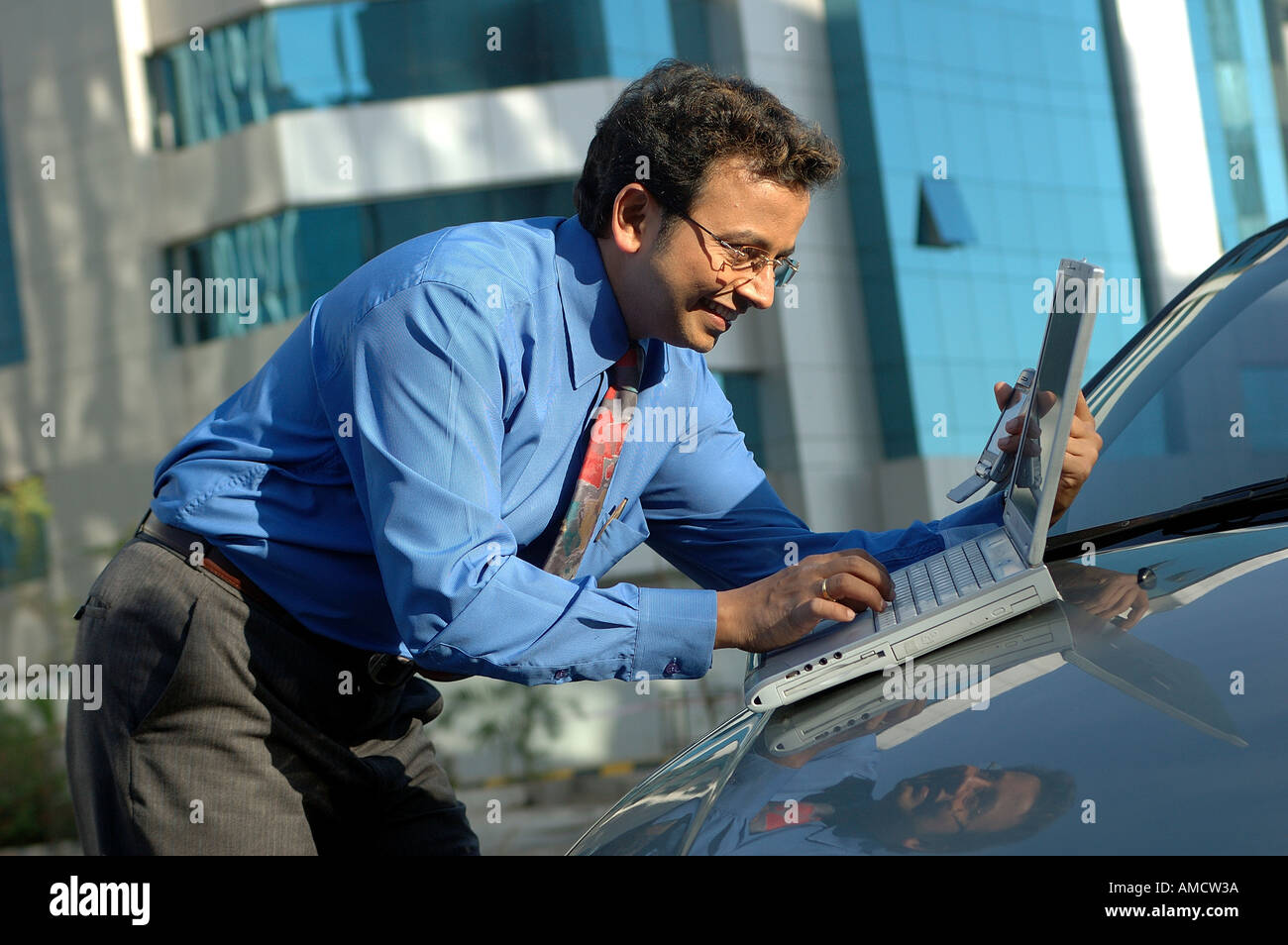 VEP72160 junge indische Executive mit Krawatte auf Computer arbeiten auf Auto bonnett Stockfoto