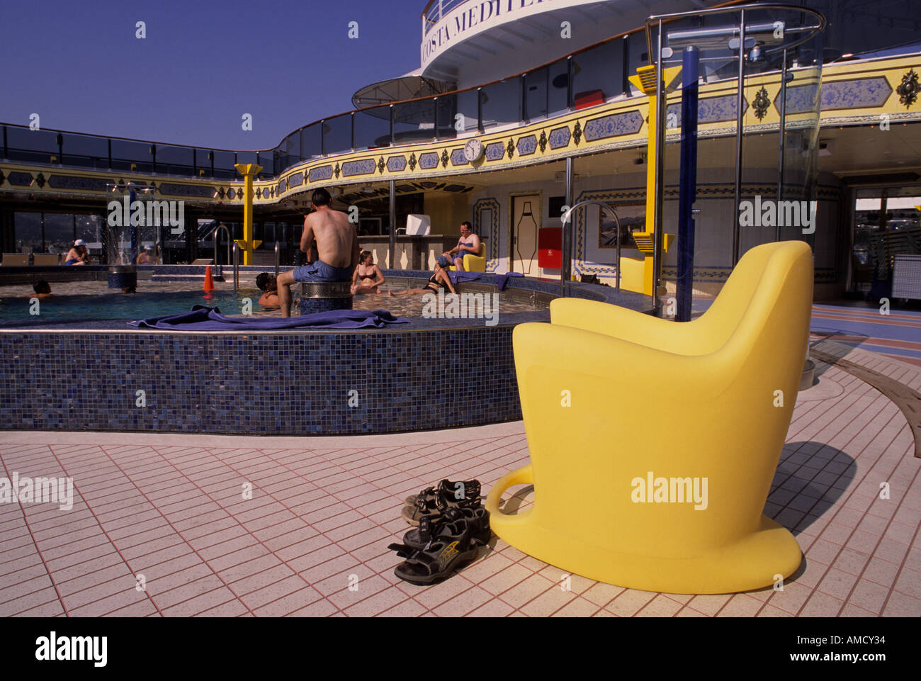 gelber Kunststoff Sessel und Sandalen im Swimming Pooldeck des Kreuzfahrtschiff Costa Mediterranea Stockfoto
