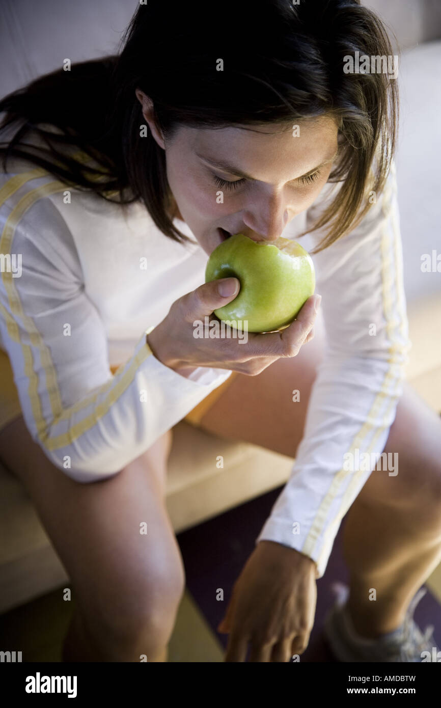 Frau sitzt und grünen Apfel essen Stockfoto