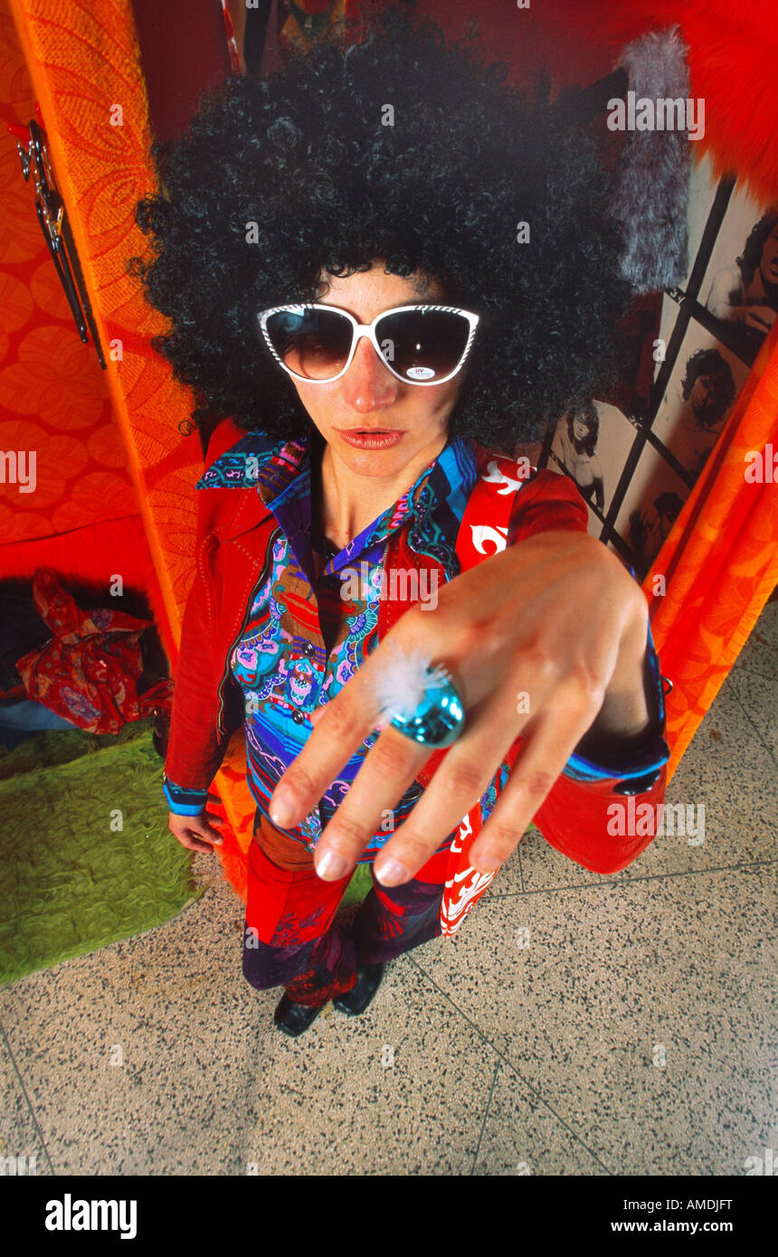 Frau mit schwarze Afro Perücke mit Sonnenbrille 70er Jahre Kleidung an Hand mit Ring in Richtung Kamera Stockfoto