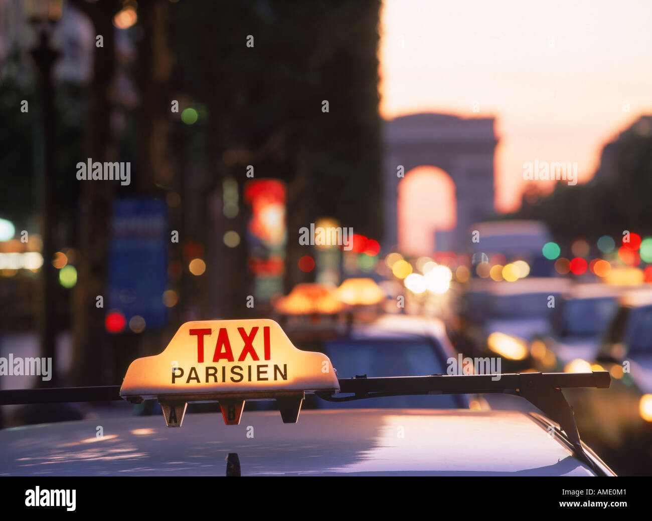 Taxis und Verkehr in der Abenddämmerung auf der Champs-Elysées mit dem Arc de Triomphe in Paris Stockfoto