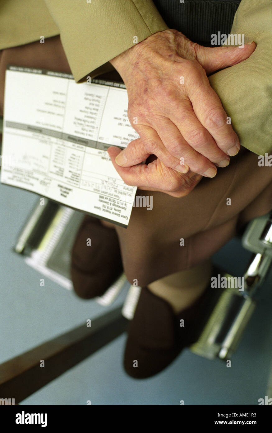 Hände eines älteren Patienten im Rollstuhl halten Patientenakten, Gesundheitszentrum, London, UK. Stockfoto