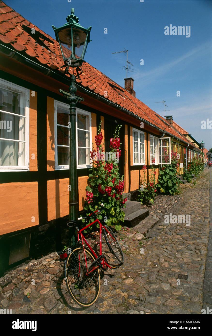 Ein Fahrrad gelehnt eine dekorative Laterne vor einer Reihe von Farbe gewaschen Fachwerkhäusern mit steil geneigte Ziegeldächer in Rønne auf Bornholm Stockfoto