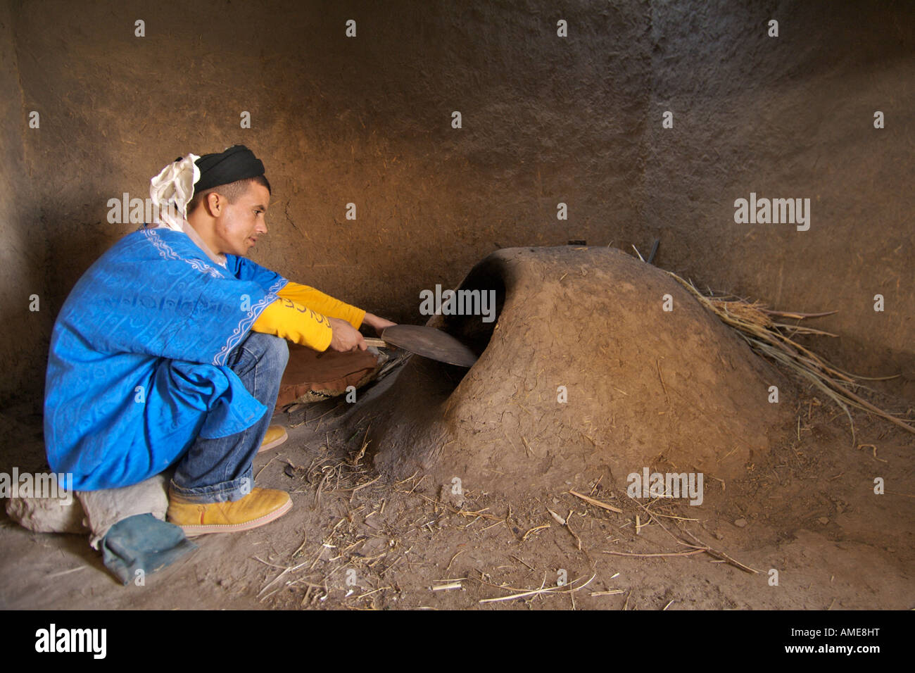 Ein Berber Mann neben einem alten Dorfbackstube in Merzouga, einem traditionellen Berberdorf im östlichen Marokko. Stockfoto