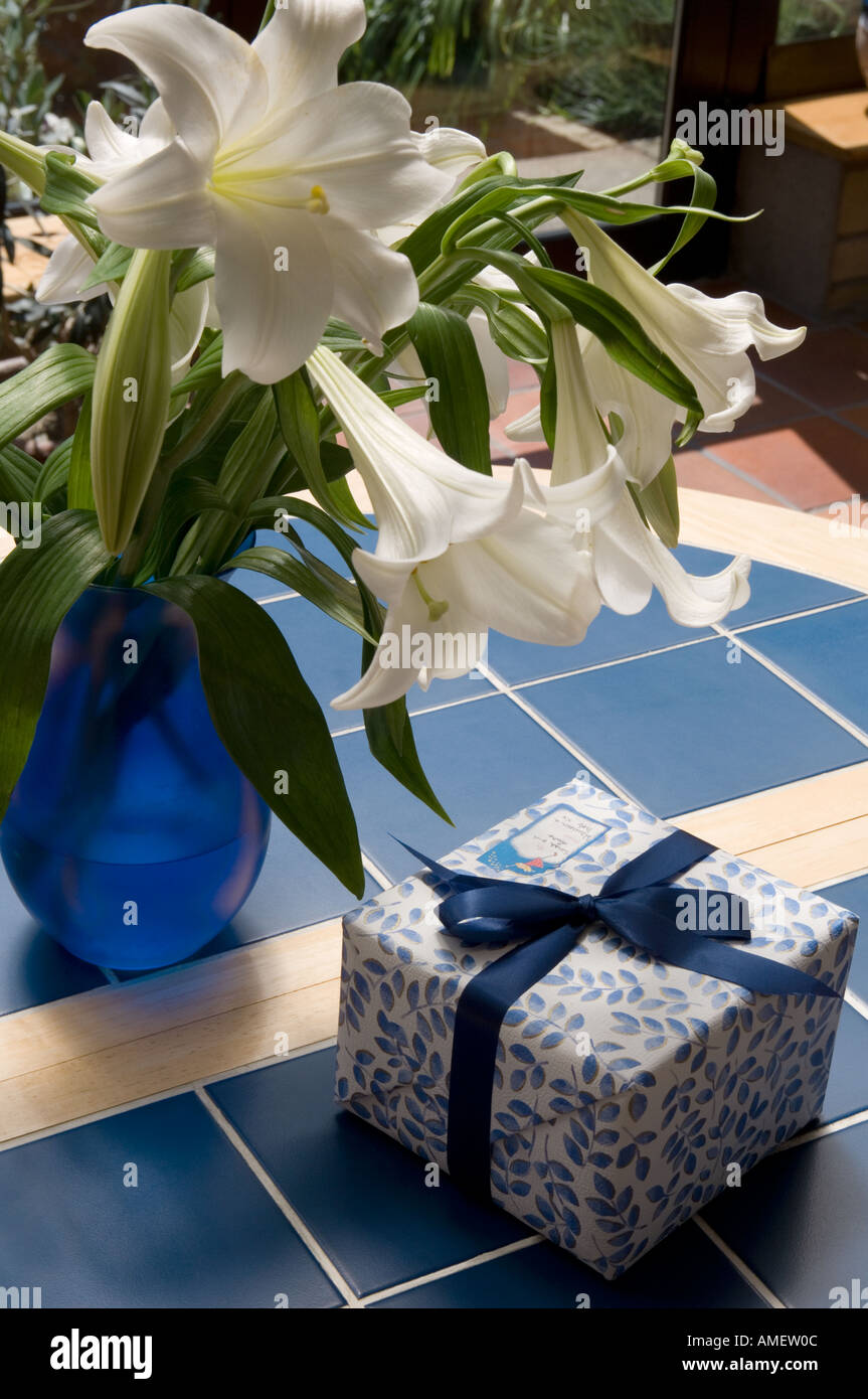 Ein Geschenk verpackt auf einem Tisch mit einer Vase mit Lilien vorhanden Stockfoto