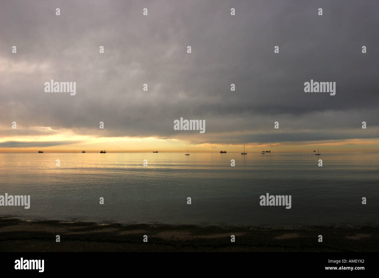 Einige Schiffe in das Meer am Strand von Puerto Madryn während Sonnenaufgang Dämmerung in Peninsula de Valdez, Chubut, Patagonien, Argentinien. Stockfoto