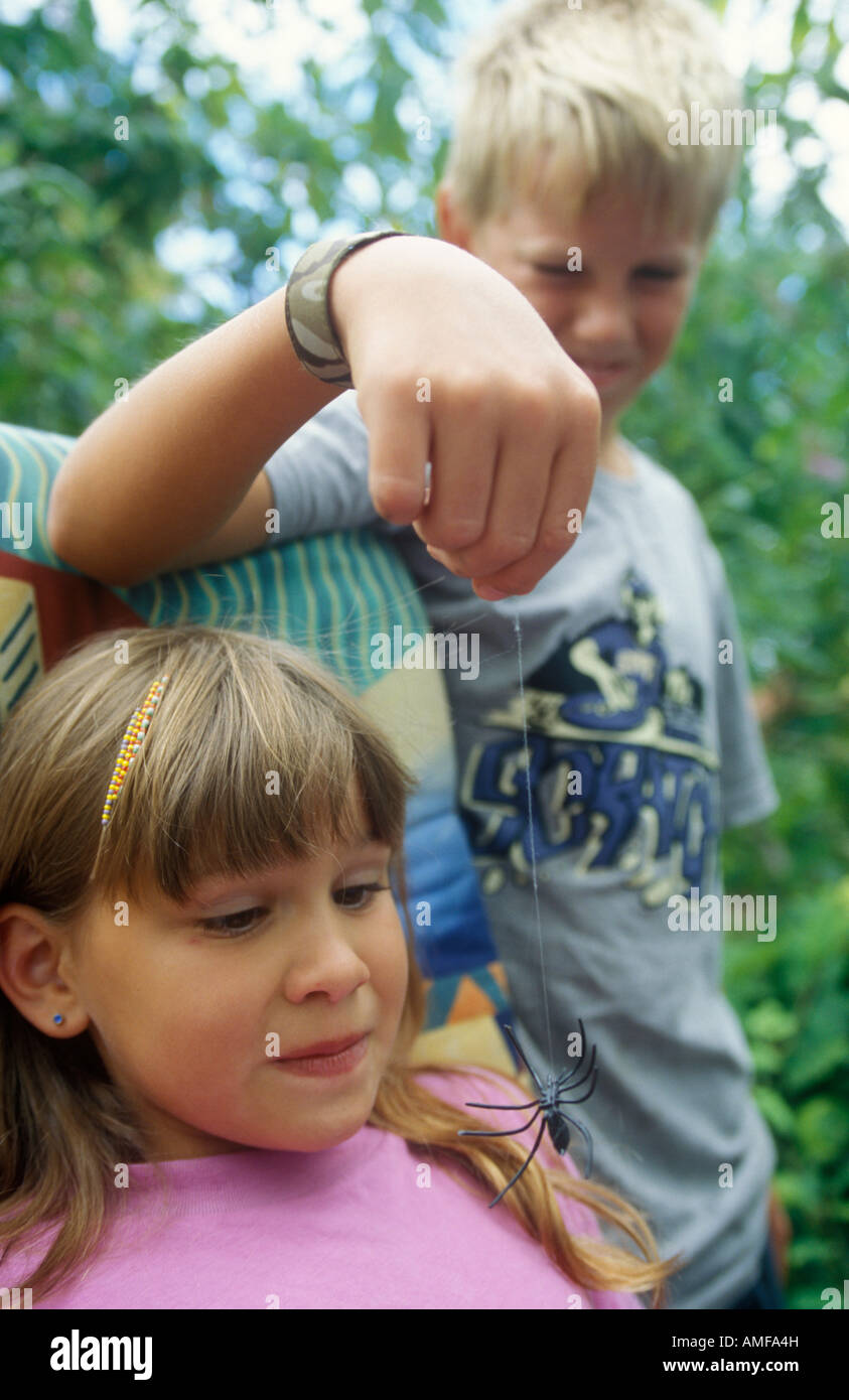 kleiner Junge beängstigend seine kleinere Schwester mit einer Spielzeug-Spinne Stockfoto