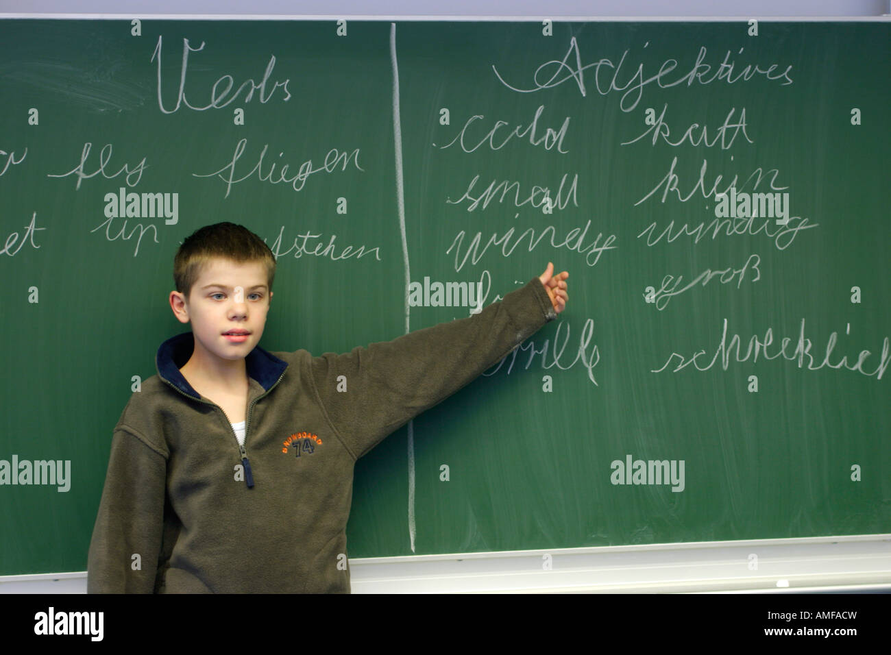 ein kleiner Junge hat deutsche und englische Wörter auf dem Brett in der Schule geschrieben. Stockfoto