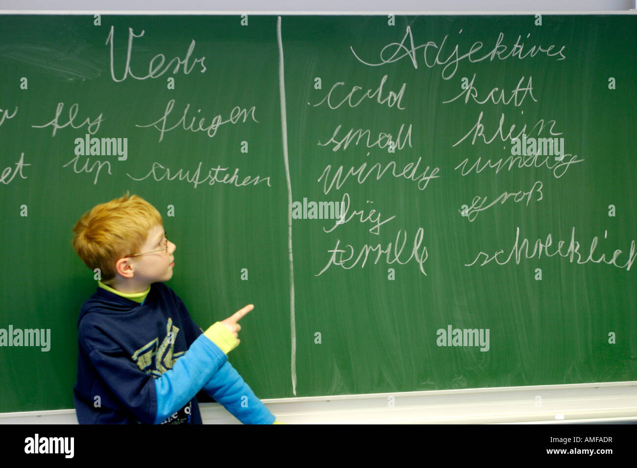 ein kleiner Junge hat deutsche und englische Wörter auf dem Brett in der Schule geschrieben. Stockfoto