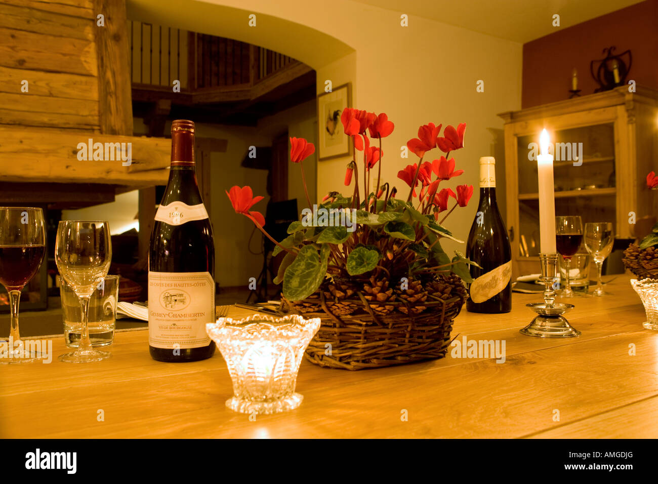 Kerzen-Wein und Alpenveilchen am Esstisch Stockfoto