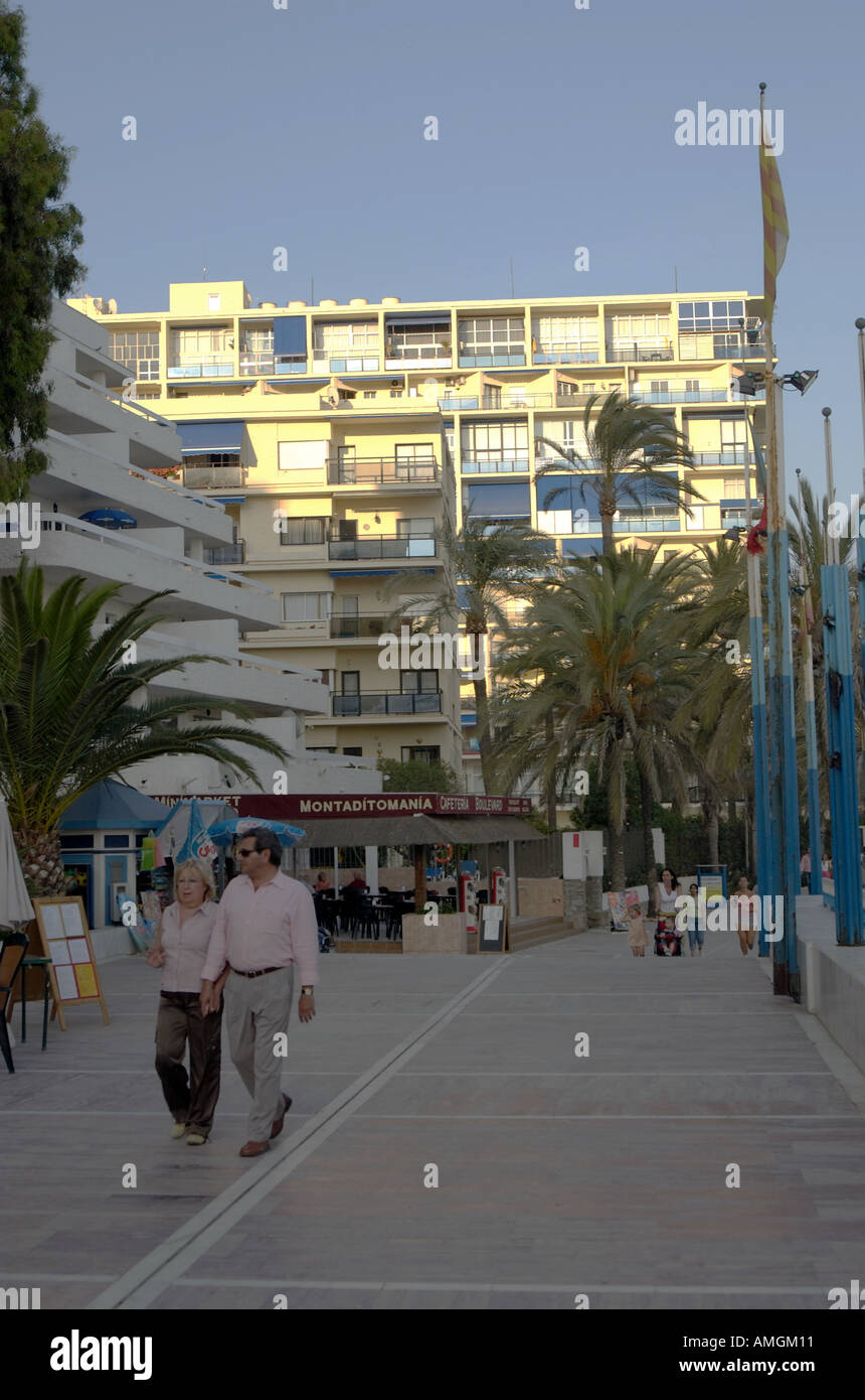 Touristischen Spaziergang entlang der Promenade, gesäumt von high-Rise Wohnungen, Läden, & Restaurants in Marbella, Andalusien Südspanien Stockfoto