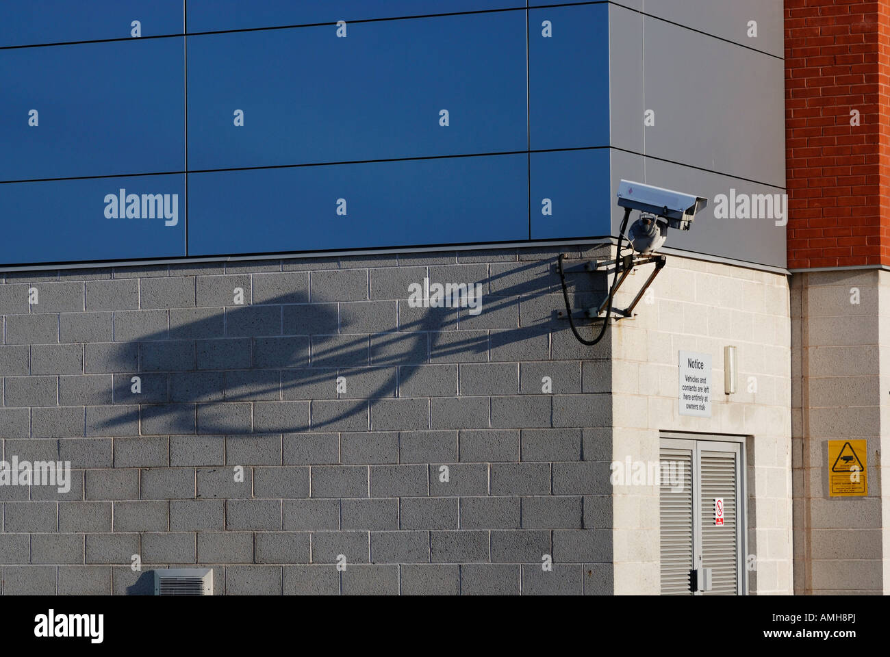 Überwachungskamera wirft einen langen Schatten auf Seite des Gebäudes montiert. Stockfoto