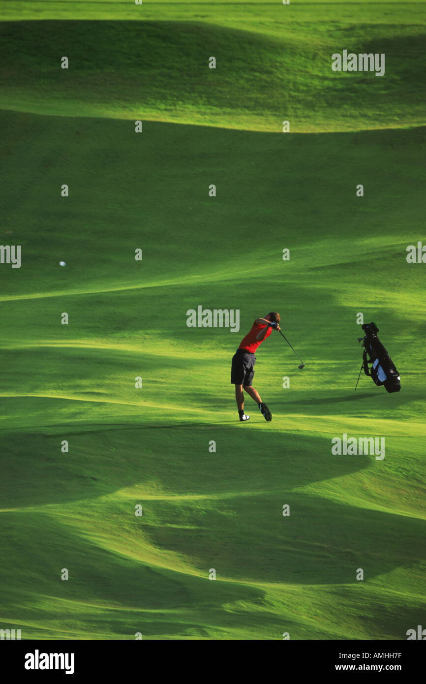 Männlichen Golfer schlagen Eisen schoss aus üppigen grünen Fairway bei schwachem Licht Stockfoto