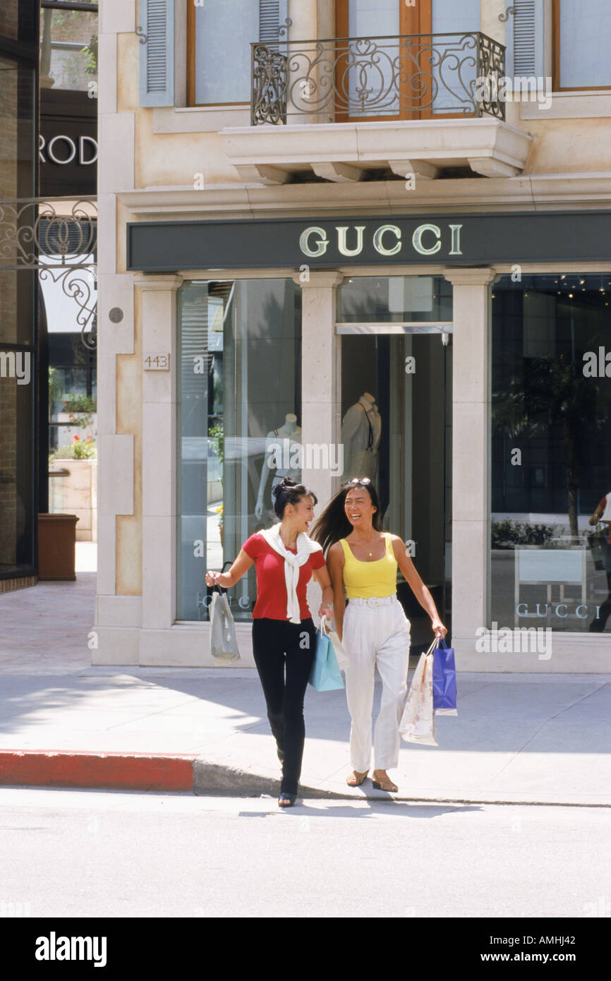 Zwei asiatische Schwestern Kreuzung Rodeo Drive mit Einkaufstüten in Beverly Hills Stockfoto