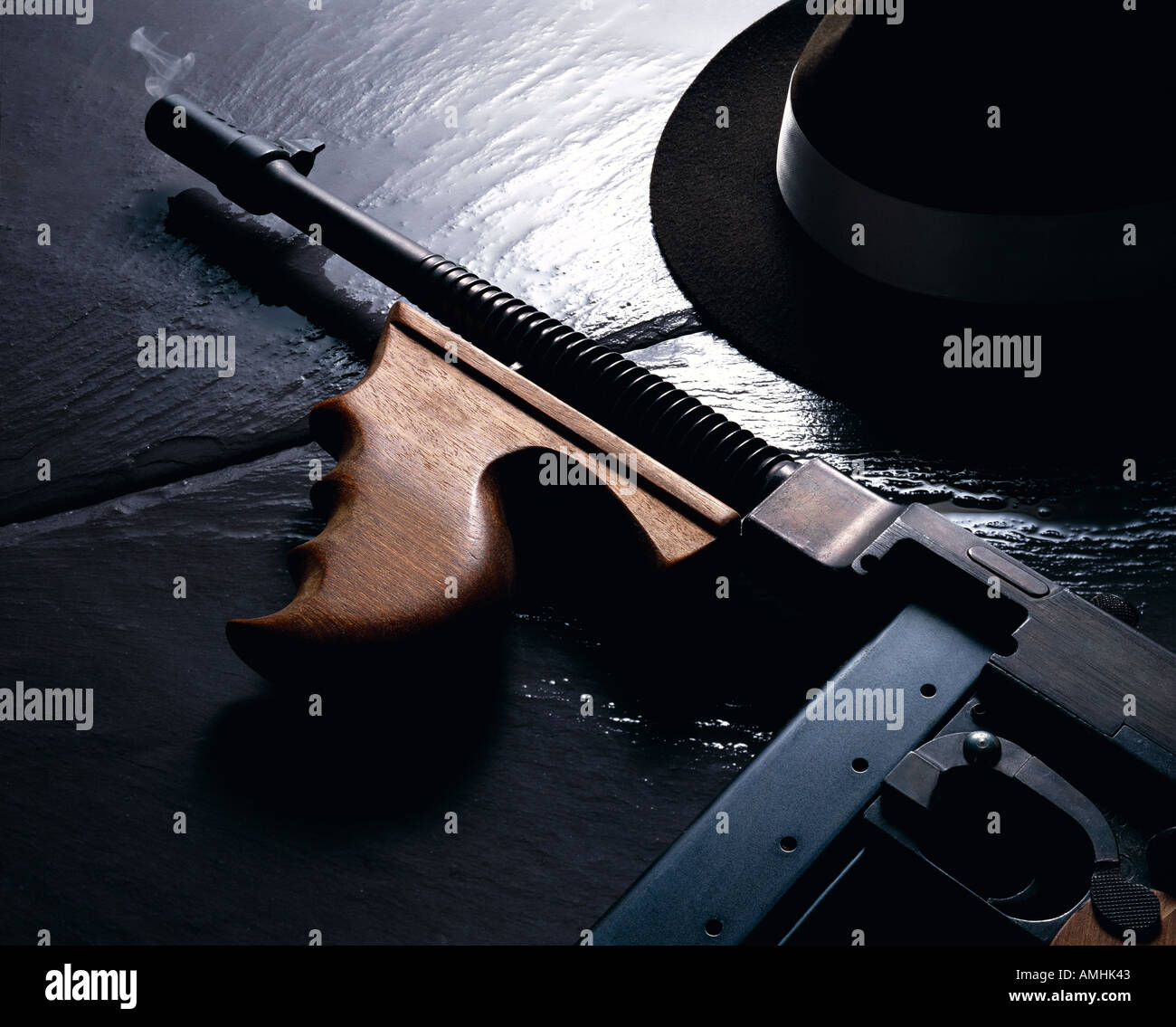 Mafia-Stillleben-Rauchen-Maschinengewehr und Hut auf kalten nassen Schiefer Stockfoto
