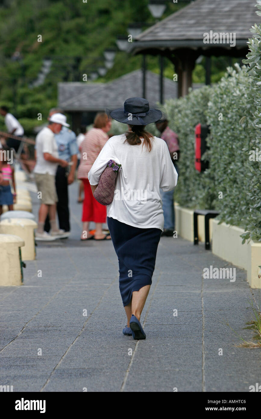 Frau in flachen Schuhen mit Strohhut und Tasche Spaziergänge entlang der Hafenpromenade Gustavia St Barts Stockfoto