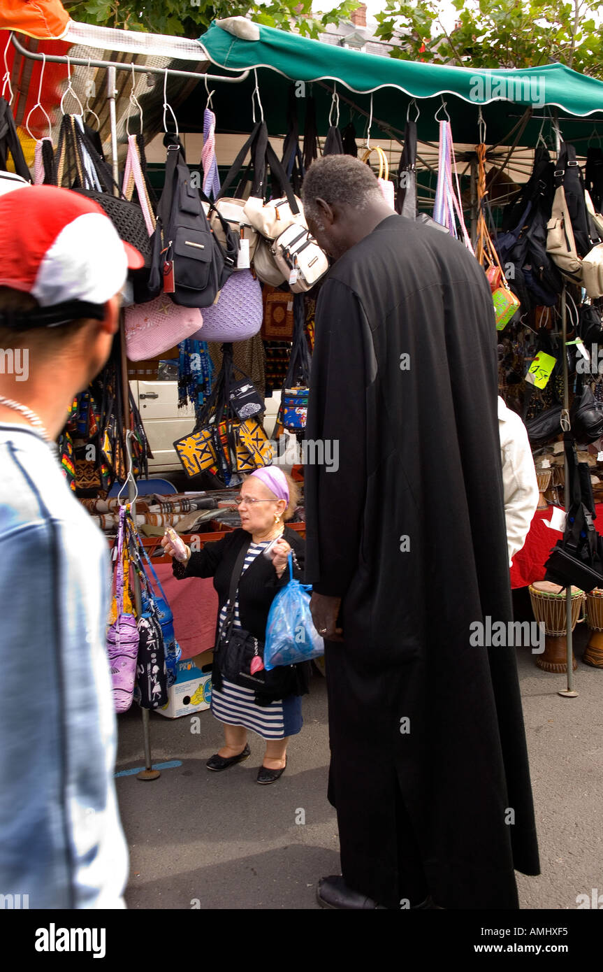 Sehr kurze Frau Kauf eine Geldbörse von einem sehr hohen afrikanischen Mann an einem Marktstand in Trouville Frankreich Stockfoto
