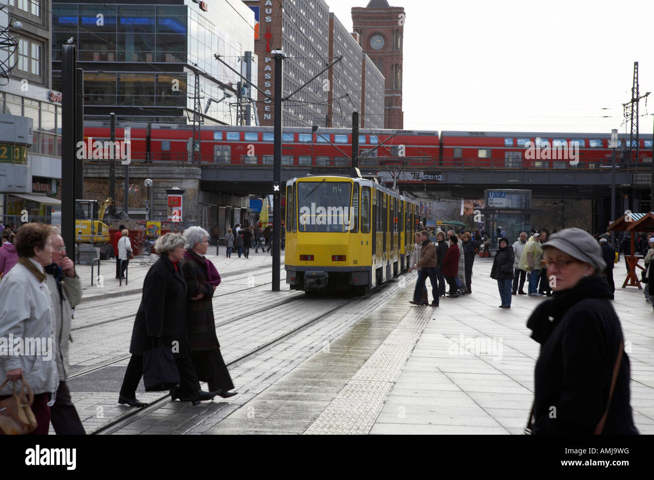 BVG Berlin gelbe Straßenbahn mit Passanten und Zug Freileitung obwohl Alexanderplatz Berlin Deutschland reisen Stockfoto
